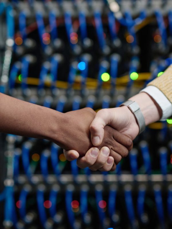 Close-up of server engineers shaking hands during teamwork in server room